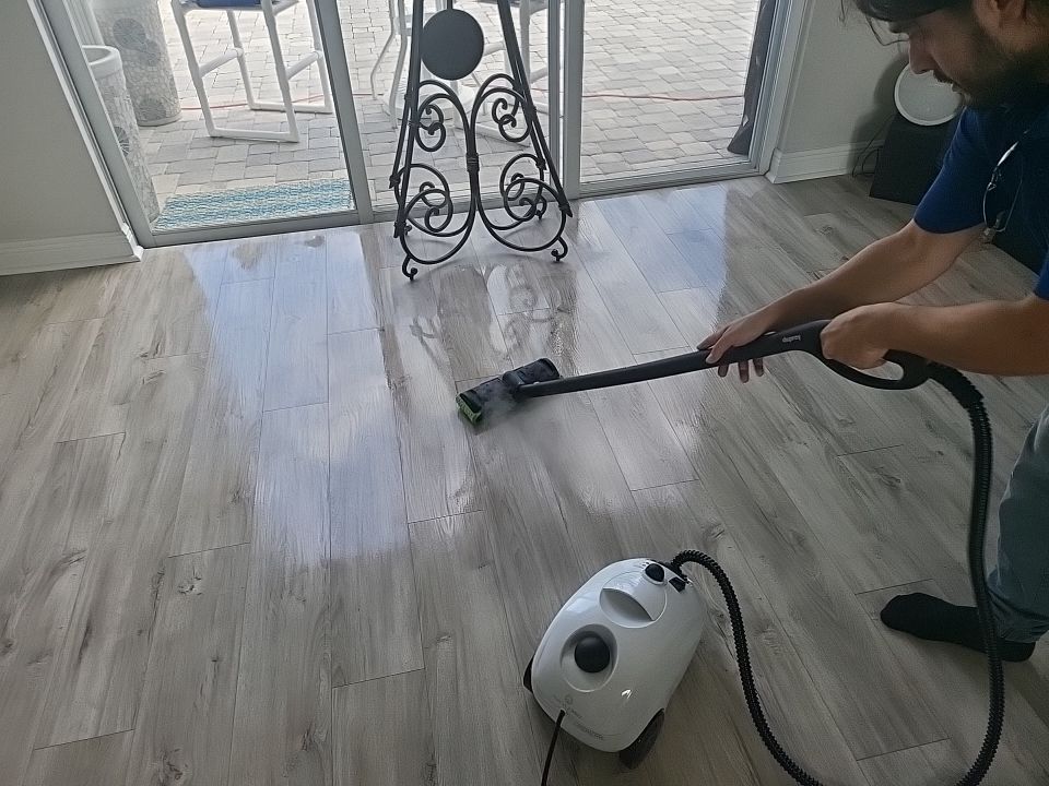 Technician steam cleaning restored hardwood floors in waterfront home